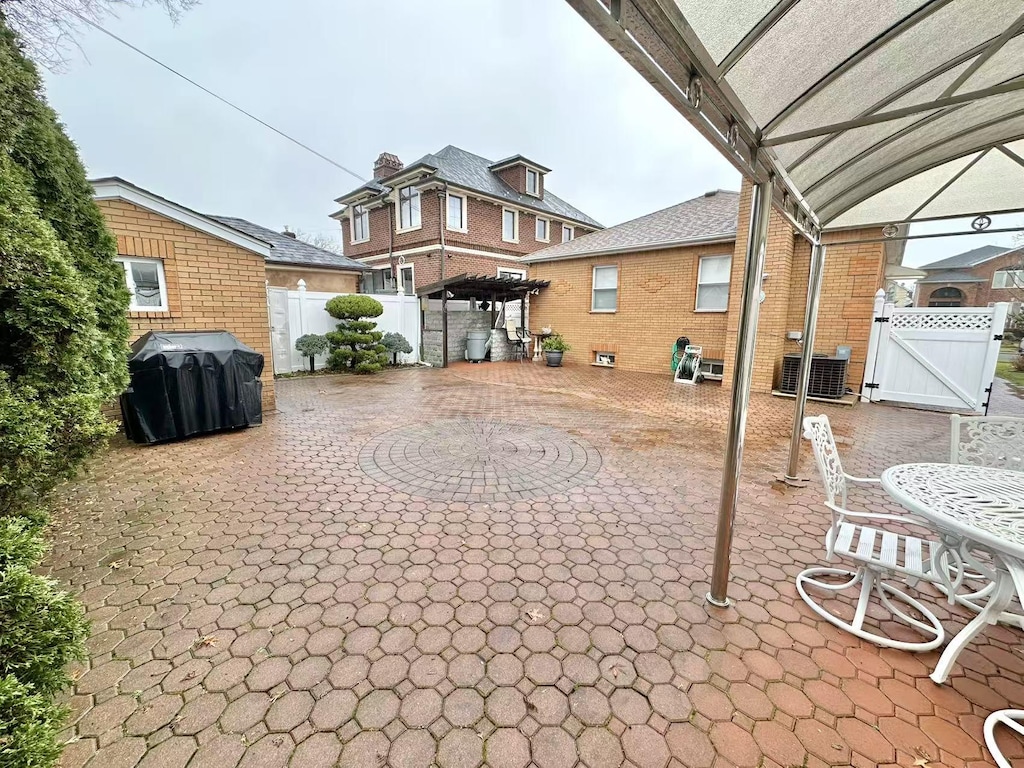 view of patio with a gate, grilling area, fence, and central AC