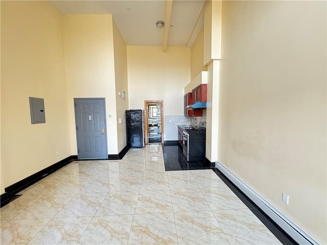 kitchen featuring baseboard heating, a high ceiling, baseboards, a sink, and light marble finish floors