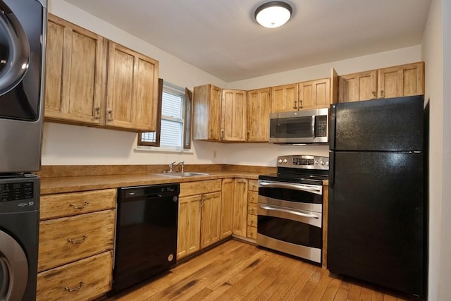 11 The Blvd Unit A4, Cold Spring, NY 10516 - kitchen with black appliances, stacked washer / dryer, a sink, and light wood finished floors