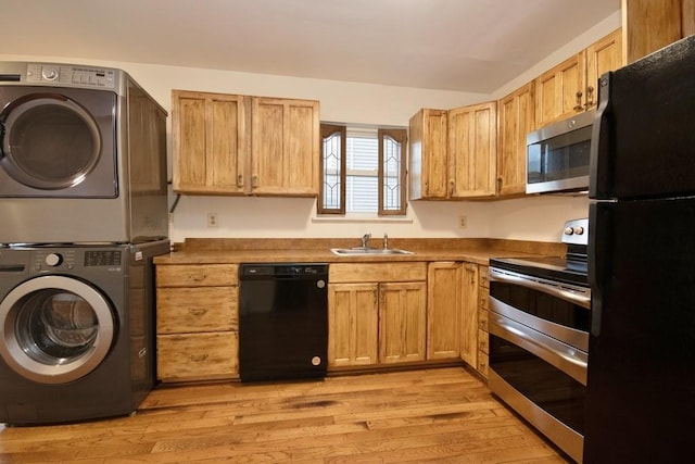 11 The Blvd Unit A4, Cold Spring, NY 10516 - kitchen featuring black appliances, stacked washer and clothes dryer, light wood finished floors, and a sink