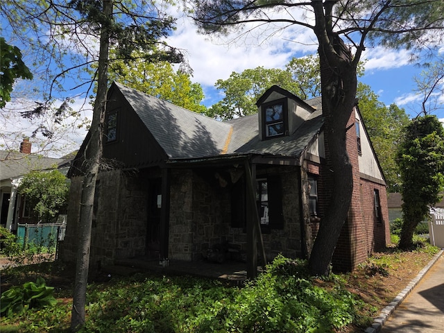 view of front of property with roof with shingles and stone siding