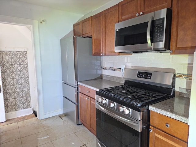 kitchen featuring stainless steel appliances, backsplash, baseboards, light tile patterned flooring, and brown cabinetry
