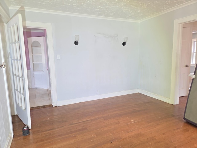 spare room featuring wood finished floors, ornamental molding, and baseboards