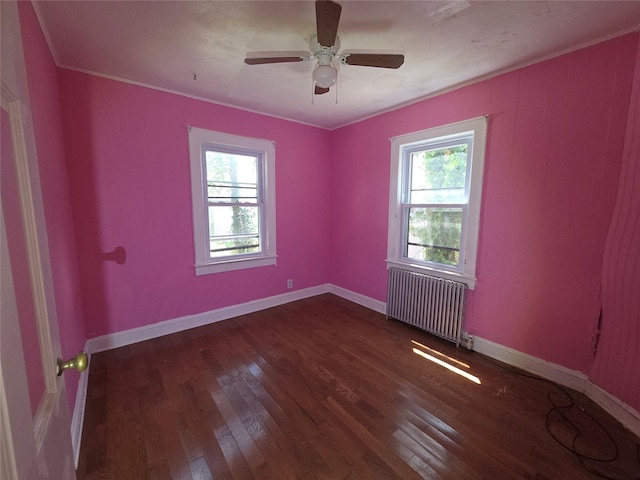 spare room with radiator heating unit, wood finished floors, a ceiling fan, baseboards, and crown molding