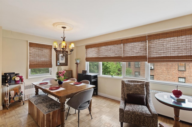 dining space with a chandelier, radiator heating unit, and baseboards