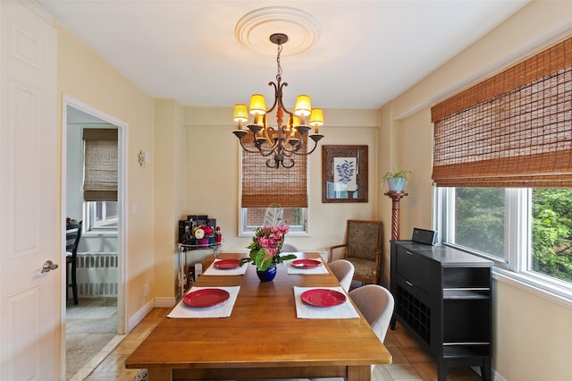 dining space with a chandelier, light wood-type flooring, radiator heating unit, and baseboards