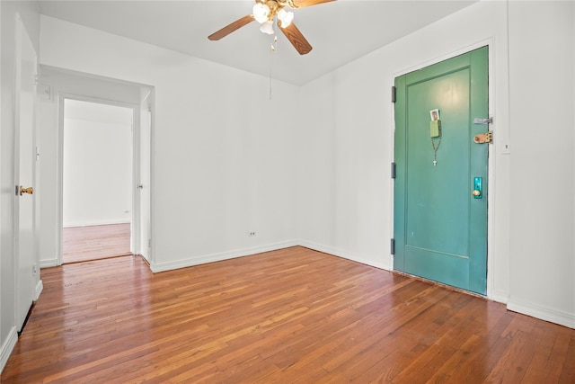 unfurnished room featuring ceiling fan, wood finished floors, and baseboards