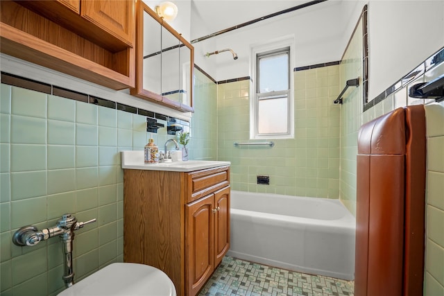 bathroom with tile walls, shower / washtub combination, vanity, toilet, and tile patterned floors