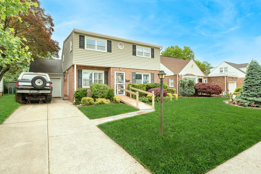 11 Durham Rd, New Hyde Park, NY 11040 - colonial home with brick siding, a front lawn, an attached garage, and concrete driveway