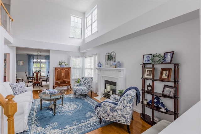 40 Ethan Cir, Middle Island, NY 11953 - living room with wood finished floors, a towering ceiling, a fireplace with flush hearth, and a chandelier