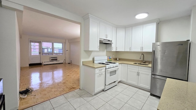 160-10 89th Ave Unit 9A, Jamaica, NY 11432 - kitchen with white range with gas stovetop, freestanding refrigerator, a sink, under cabinet range hood, and light countertops