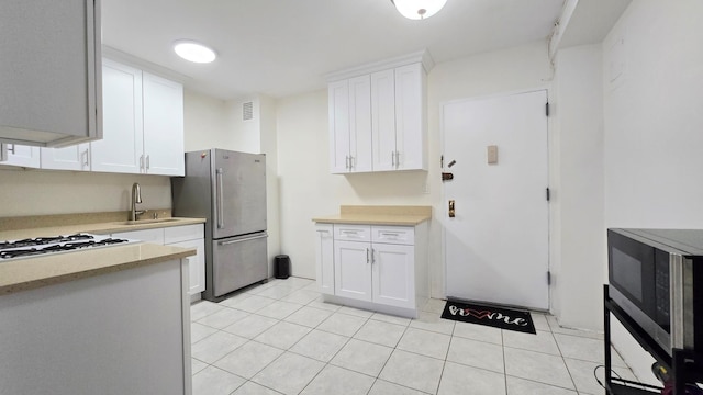 160-10 89th Ave Unit 9A, Jamaica, NY 11432 - kitchen with freestanding refrigerator, white gas cooktop, white cabinets, a sink, and light tile patterned floors