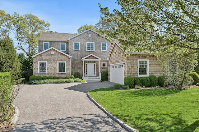 shingle-style home with driveway, a garage, and a front lawn