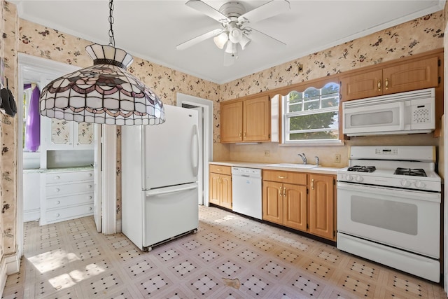 kitchen with white appliances, light countertops, a sink, wallpapered walls, and a ceiling fan