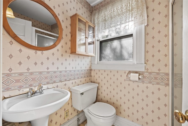 bathroom featuring wallpapered walls, a sink, and toilet