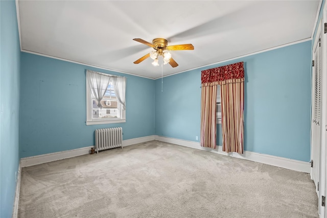 carpeted empty room with radiator heating unit, ceiling fan, baseboards, and ornamental molding