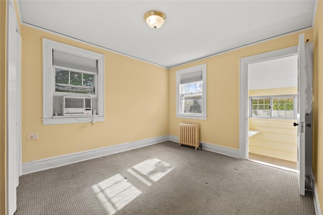 unfurnished room featuring radiator, carpet flooring, baseboards, and cooling unit