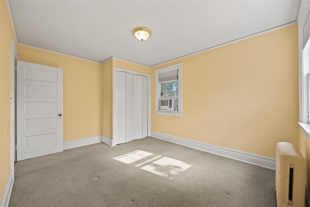 unfurnished bedroom featuring carpet, baseboards, a closet, and radiator