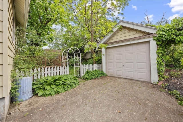 detached garage with concrete driveway and fence