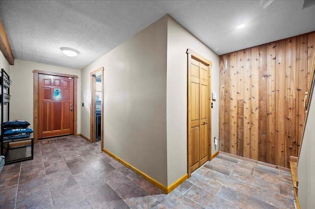 190 1st St, Buchanan, NY 10511 - entrance foyer featuring a textured ceiling, baseboards, stone finish flooring, and wood walls