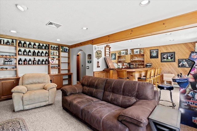 190 1st St, Buchanan, NY 10511 - carpeted living area featuring arched walkways, wood walls, recessed lighting, bar, and a textured ceiling