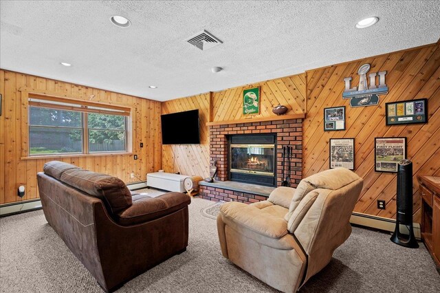 190 1st St, Buchanan, NY 10511 - living room featuring carpet flooring, a textured ceiling, wooden walls, baseboard heating, and a brick fireplace