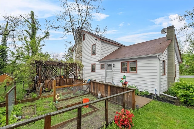 17 Sylvan Lake Rd, Lagrangeville, NY 12540 - rear view of house with a chimney, a vegetable garden, roof with shingles, and fence