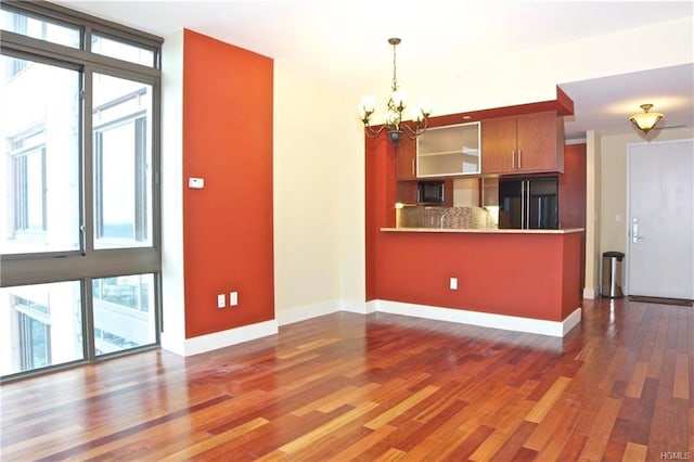 kitchen featuring refrigerator, plenty of natural light, a chandelier, and wood finished floors