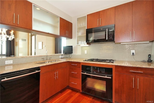 kitchen featuring black appliances, a sink, dark wood-style floors, decorative backsplash, and light stone counters
