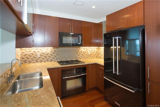 kitchen with black appliances, a sink, backsplash, wood finished floors, and recessed lighting