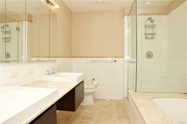full bath with a shower stall, toilet, tile walls, and double vanity