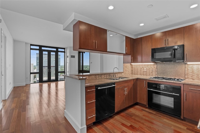 175 Huguenot St Unit 1808, New Rochelle, NY 10801 - kitchen featuring black appliances, decorative backsplash, wood finished floors, a peninsula, and open floor plan