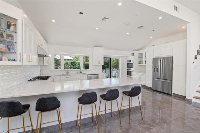 862 Fanwood Ave, North Woodmere, NY 11581 - kitchen featuring appliances with stainless steel finishes, decorative backsplash, vaulted ceiling, glass insert cabinets, and a peninsula