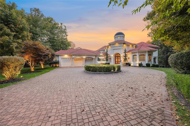 mediterranean / spanish home featuring curved driveway, a garage, and stucco siding