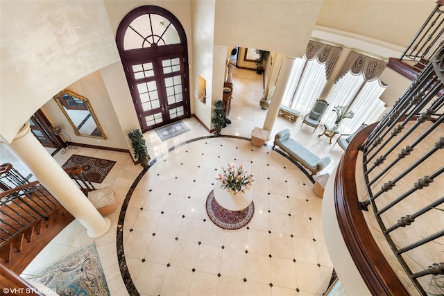 foyer featuring inlaid floor details, french doors, healthy amount of natural light, baseboards, and a high ceiling