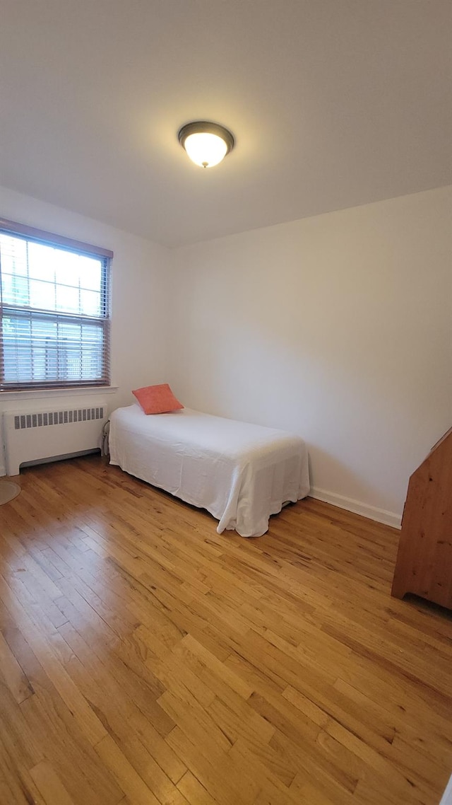 109 N Broadway Unit M12, White Plains, NY 10603 - bedroom with radiator and light wood-style flooring