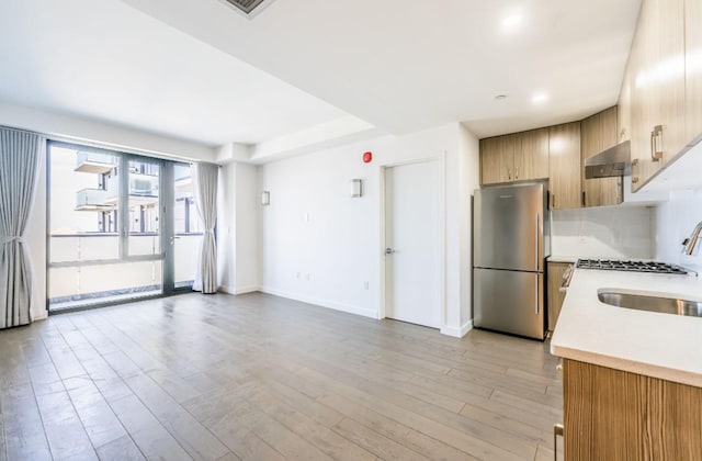 8808 Justice Ave Unit 16H, Elmhurst, NY 11373 - kitchen with freestanding refrigerator, a sink, light countertops, baseboards, and wall chimney exhaust hood