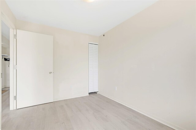 9305 37th Ave Unit 3D, Jackson Heights, NY 11372 - unfurnished bedroom featuring light wood-style floors, a closet, and baseboards