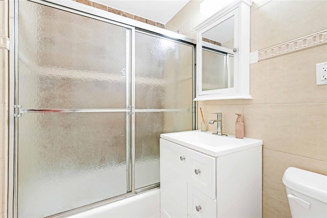 9305 37th Ave Unit 3D, Jackson Heights, NY 11372 - bathroom with tile walls, toilet, bath / shower combo with glass door, and vanity