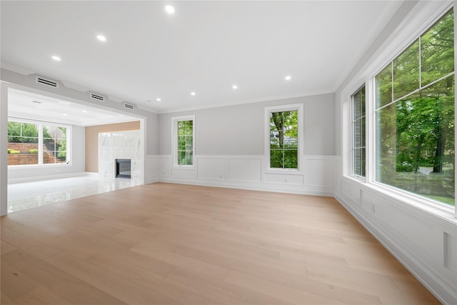 46 Snapdragon Ln, Roslyn Heights, NY 11577 - unfurnished living room with healthy amount of natural light, a wainscoted wall, ornamental molding, light wood-style floors, and a glass covered fireplace