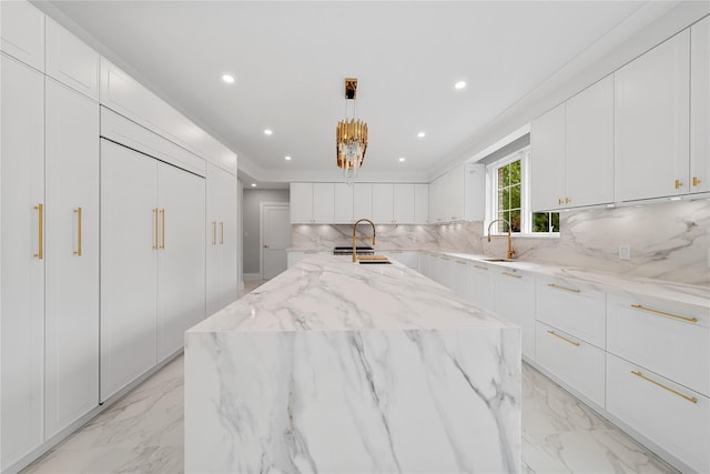46 Snapdragon Ln, Roslyn Heights, NY 11577 - kitchen featuring light marble finish flooring, a sink, decorative backsplash, a center island with sink, and white cabinets