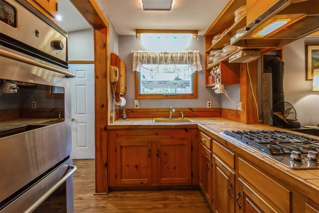 57 Empire Dr, Patterson, NY 12563 - kitchen featuring a sink, tile countertops, appliances with stainless steel finishes, brown cabinetry, and dark wood-style floors