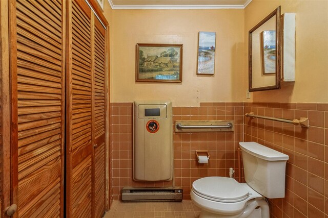 57 Empire Dr, Patterson, NY 12563 - half bath with a baseboard heating unit, tile walls, toilet, crown molding, and wainscoting