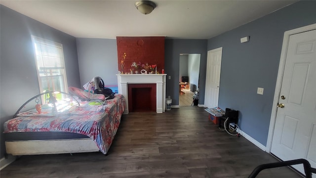 bedroom with wood finished floors, baseboards, and a fireplace
