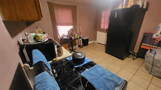 kitchen with black appliances, light tile patterned floors, and baseboards