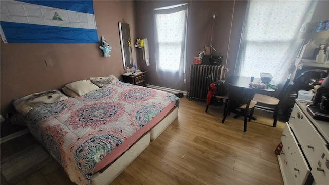 bedroom featuring radiator heating unit, wood finished floors, and an office area