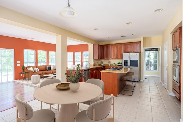 33 Avolet Ct, Mount Sinai, NY 11766 - kitchen with stainless steel appliances, a kitchen island, light countertops, brown cabinets, and a breakfast bar area