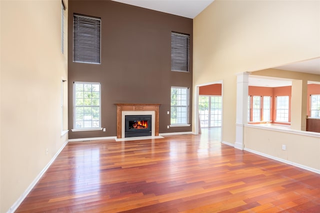 33 Avolet Ct, Mount Sinai, NY 11766 - unfurnished living room with a towering ceiling, a fireplace with flush hearth, wood finished floors, and baseboards