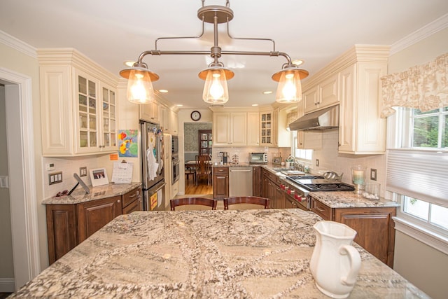 184 Dorothy Rd, West Islip, NY 11795 - kitchen with under cabinet range hood, appliances with stainless steel finishes, light stone countertops, backsplash, and ornamental molding