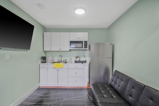 248 44th St, Lindenhurst, NY 11757 - kitchen featuring stainless steel appliances, a sink, light countertops, white cabinetry, and baseboards